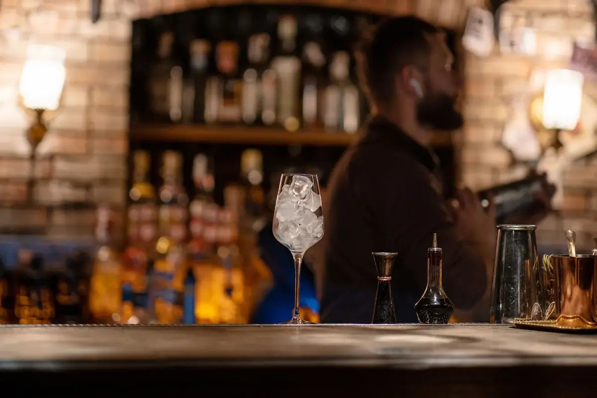 A cocktail on the bar with a bartender behind