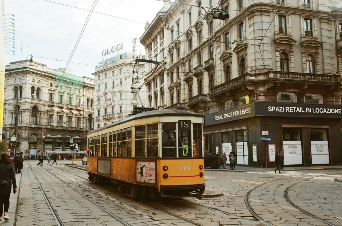A vintage tram passing shops in central Milan